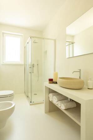 A modern bathroom with a glass-enclosed shower, a round sink, and a large mirror. - Luxury Villa Leucade, between sky and sea (Santa Maria di Leuca)