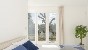 Une chambre avec un lit, une fenêtre donnant sur des arbres et une plante en pot.