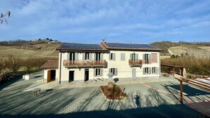 Une maison à deux étages dotée d’un balcon, d’un toit équipé de panneaux solaires et d’une allée pavée.