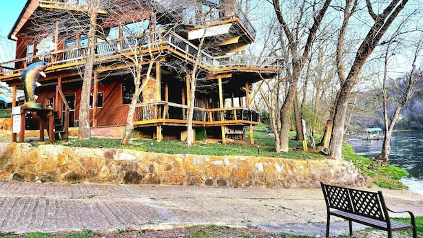 A wooden house with multiple balconies and a stone foundation, located near a body of water. - White River Lodge #3 (Lakeview)