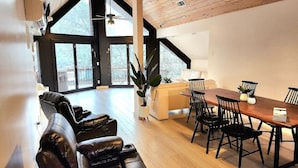 A spacious room with a large dining table, leather sofas, and a view of the outdoors. - White River Lodge #3 (Lakeview)