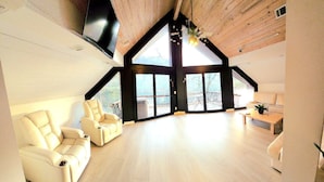 A spacious loft with high ceilings, a large window offering a view of the outdoors, and a cozy seating area with a sofa and chairs. - White River Lodge #3 (Lakeview)