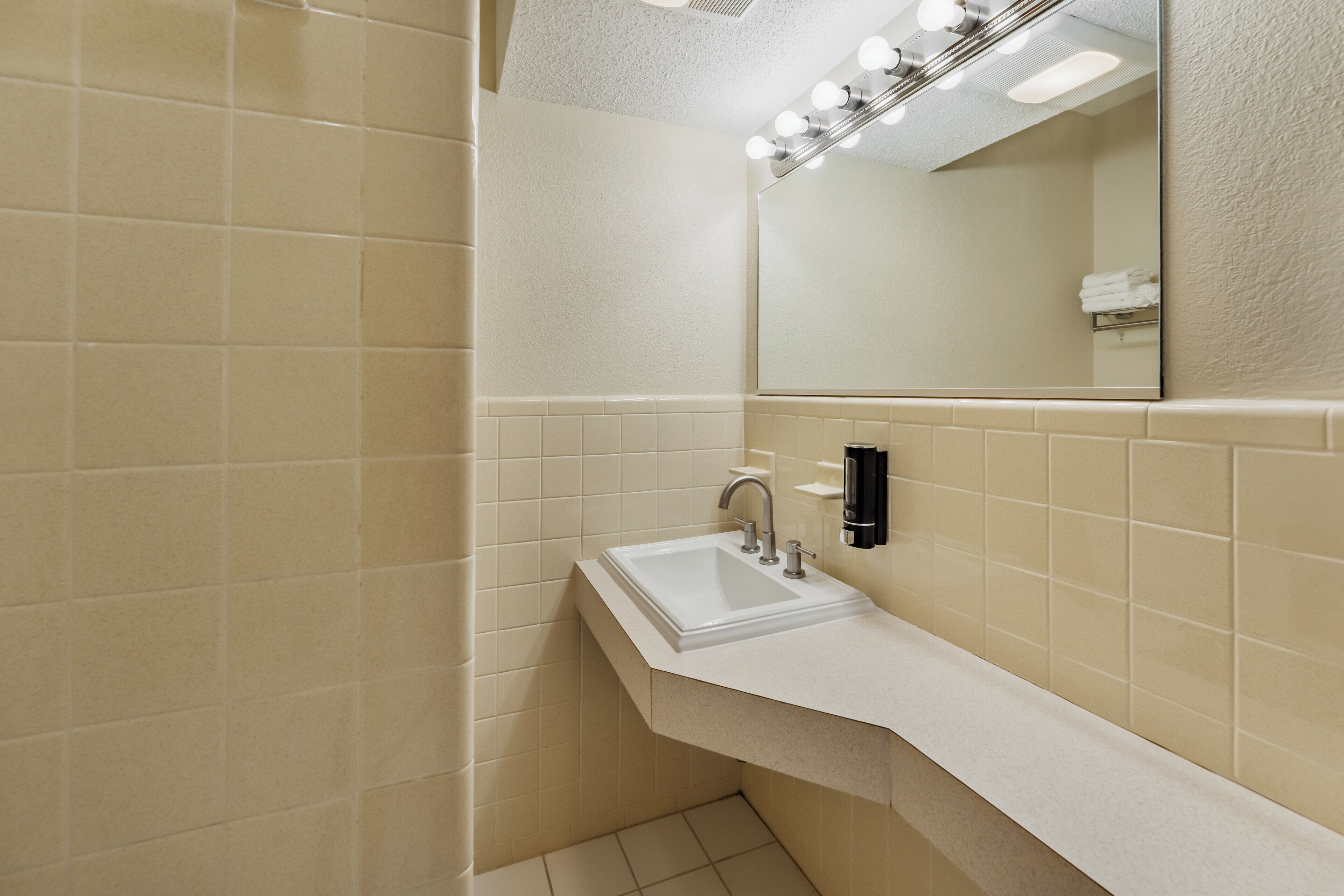 A bathroom with a sink, mirror, and lights.