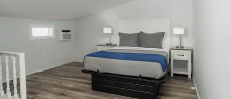 A bedroom with a bed, bedside tables, a window, and a white railing.