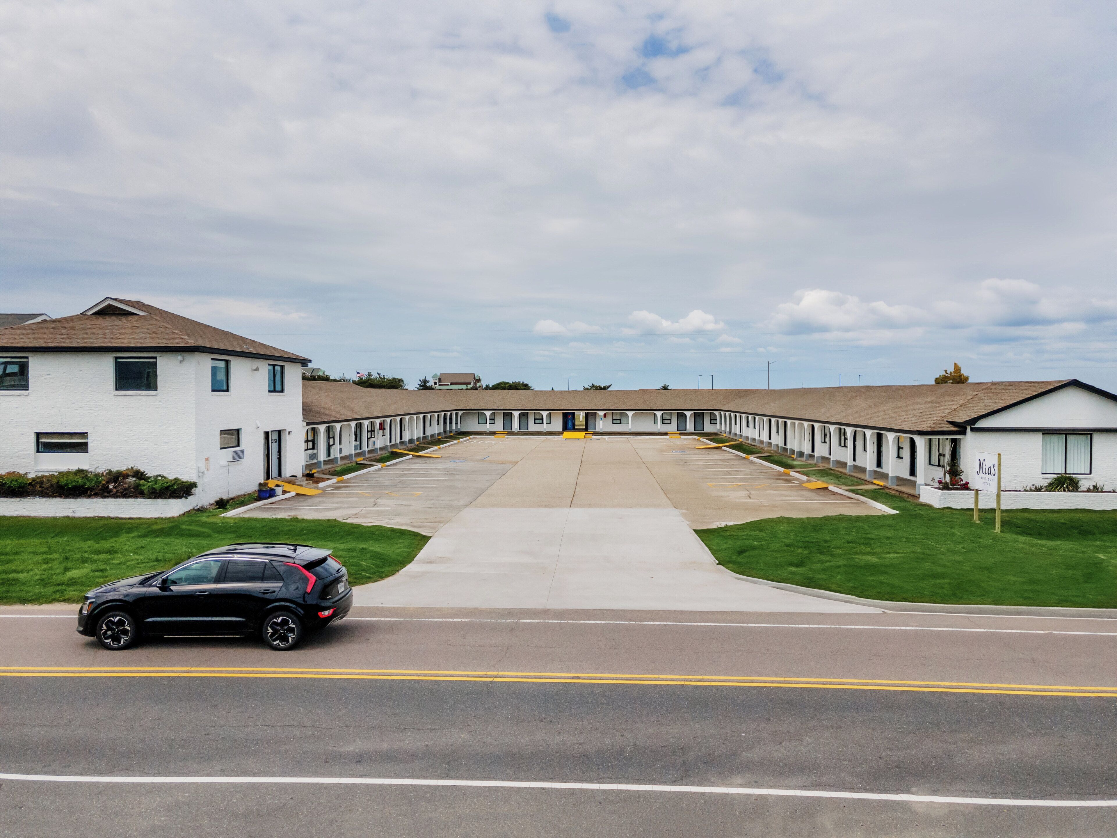 A motel with a central courtyard, individual rooms on either side, and a parking lot in front.