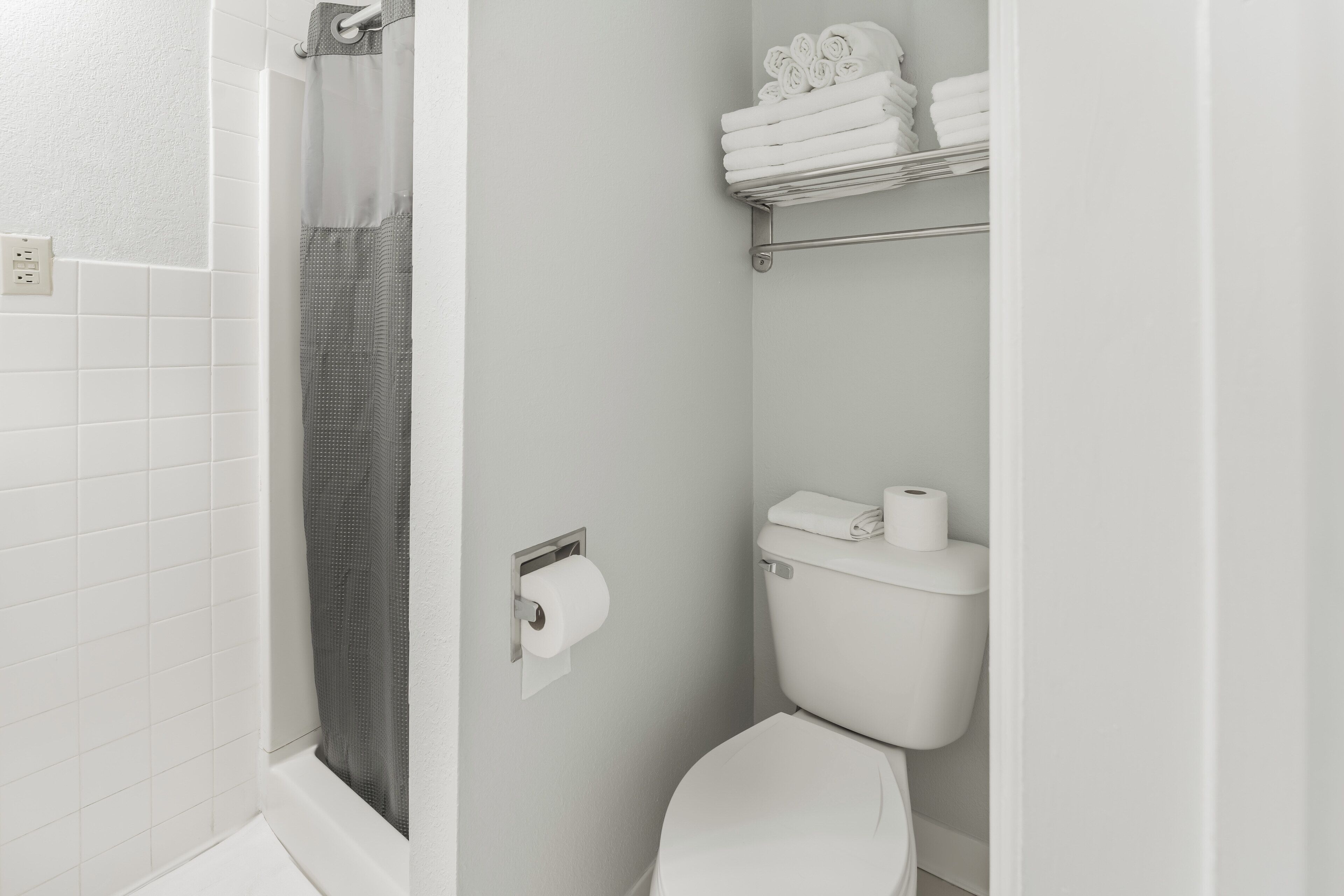 A bathroom with a shower, toilet, and towel rack.