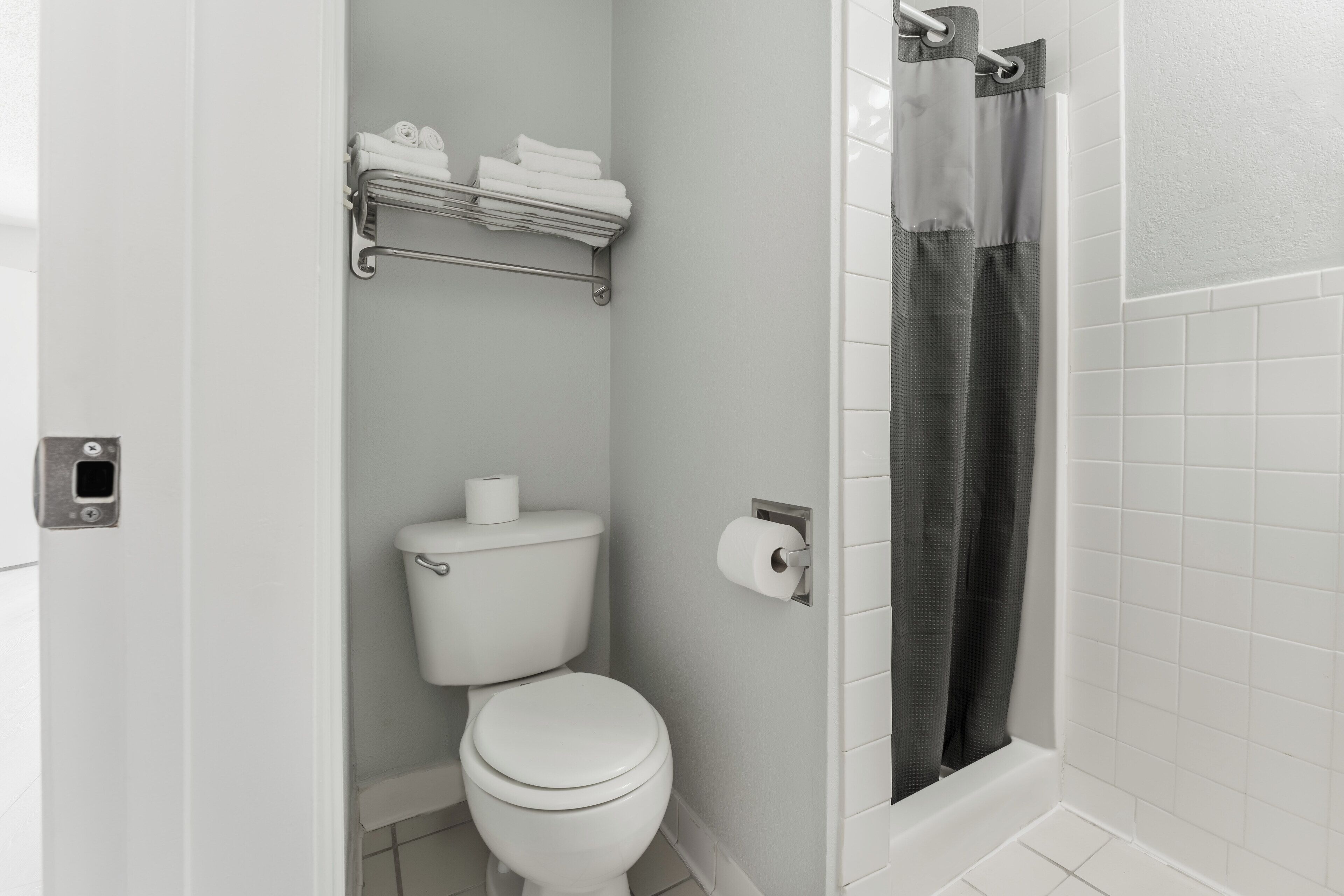 A bathroom with a toilet, a towel rack, and a shower curtain.