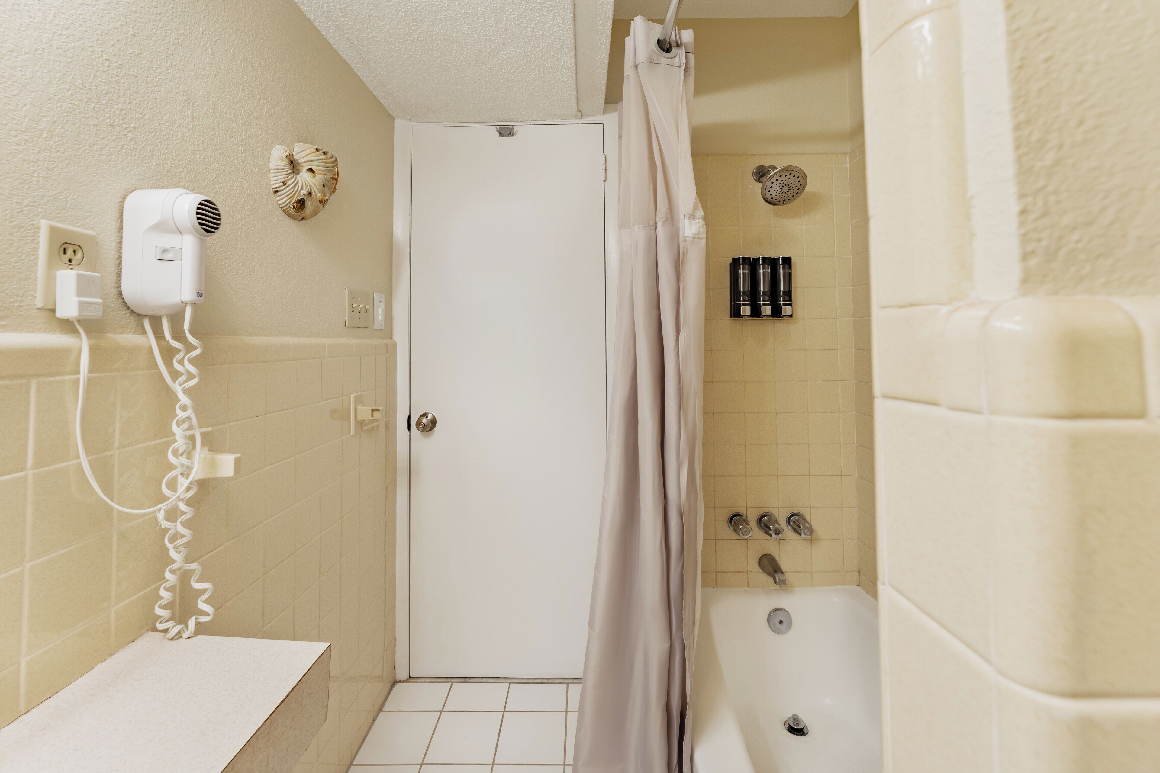 A bathroom with a shower, a hairdryer, and a towel rack.