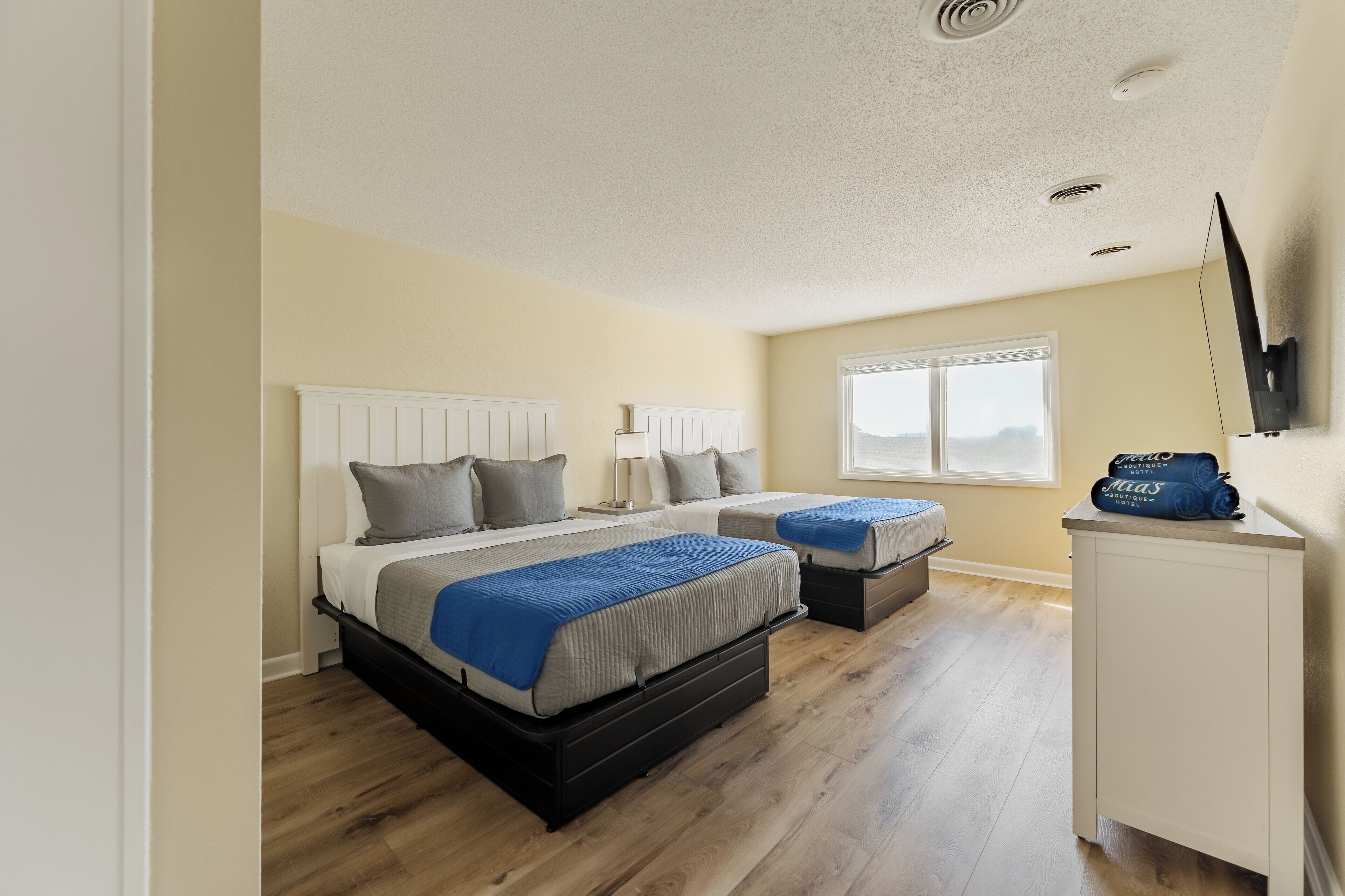 A bedroom with two beds, a white wardrobe, and a window.
