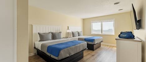 A bedroom with two beds, a white wardrobe, and a window.