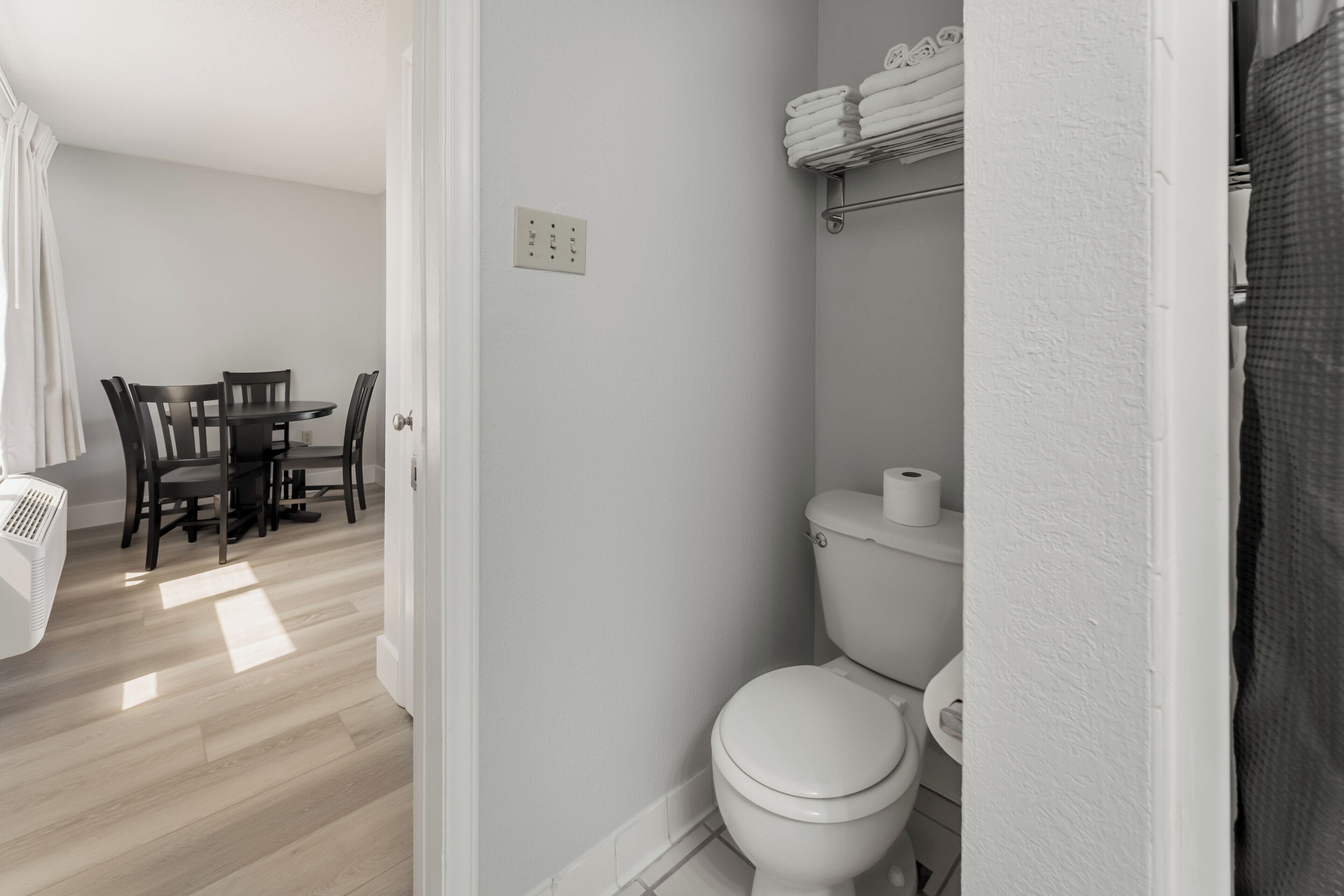 Un baño moderno con inodoro, toallero y cortina de ducha.