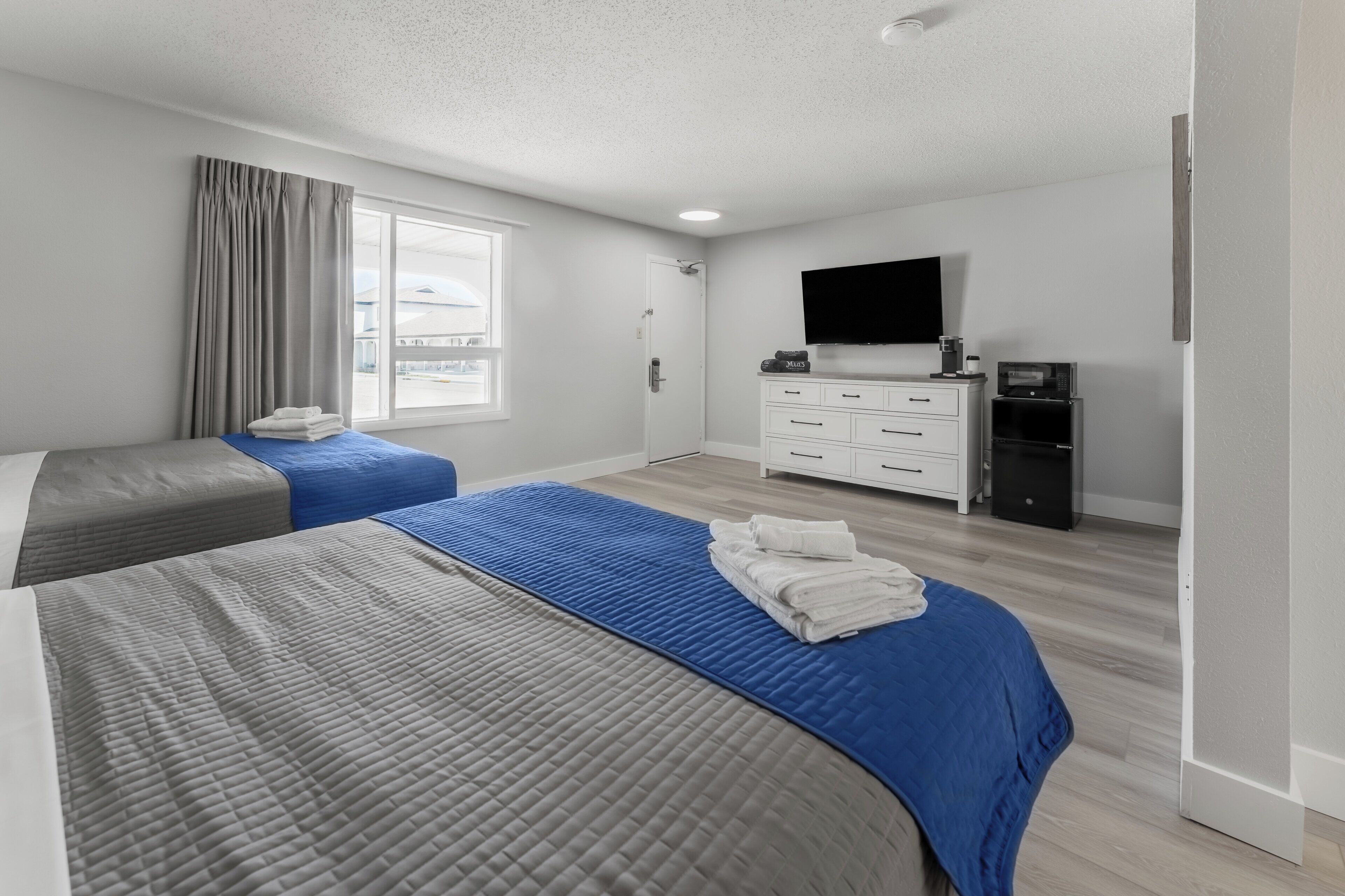 A hotel room with two beds, a TV, a desk, and a wardrobe.