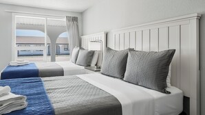 Une chambre d’hôtel avec deux lits, une grande fenêtre donnant sur un beau paysage et un balcon.