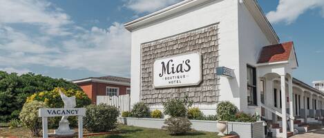 A building with a sign reading "Mia's Boutique Hotel" and a "VACANCY" sign in front.