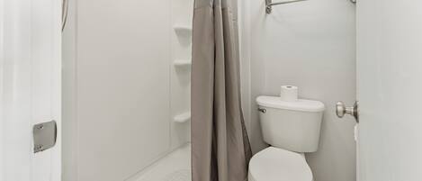 Un baño con ducha, inodoro y un perchero para toallas.