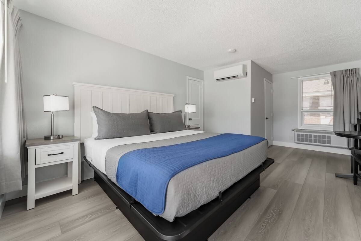 A modern bedroom with a bed, bedside tables, and a window.