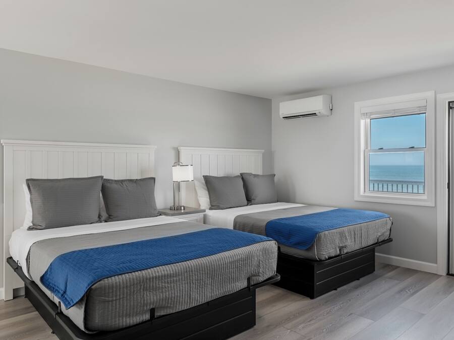 Une chambre avec deux lits, une fenêtre donnant sur un beau paysage et un appareil de climatisation.