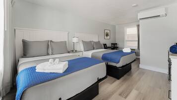 Une chambre d’hôtel avec deux lits, un bureau, une chaise et un appareil de climatisation.