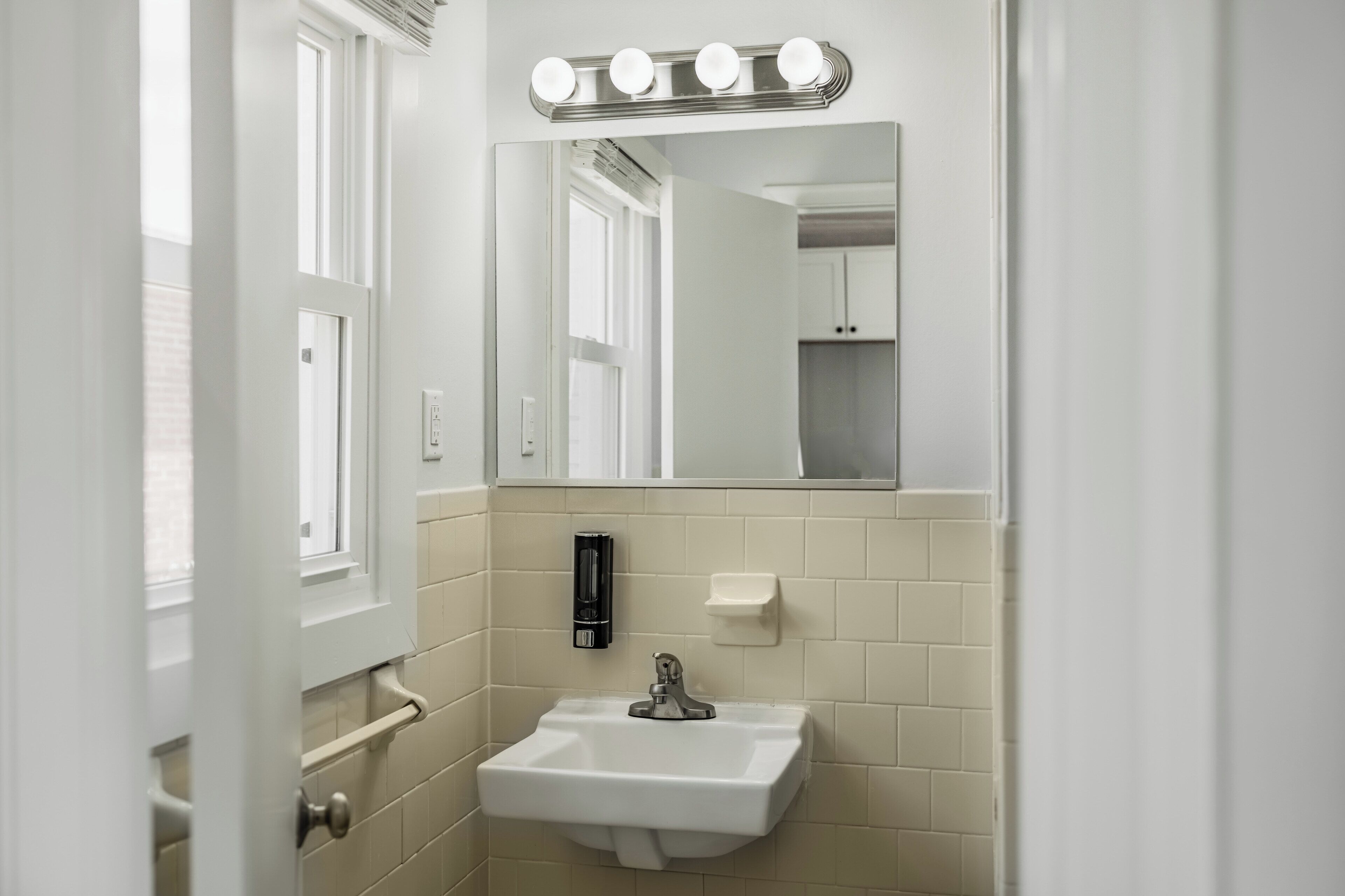 A bathroom with a sink, mirror, and vanity lights.