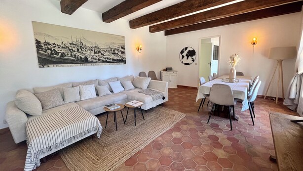 A living room with a sofa, a dining table with chairs, a rug, and a painting on the wall. - Maison 5 Chambres Cavalaire sur Mer, vue mer Panoramique (Cavalaire-sur-Mer)
