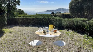An outdoor seating area with a table and chairs, a view of the sea, and a hedge in the background. - Maison 5 Chambres Cavalaire sur Mer, vue mer Panoramique (Cavalaire-sur-Mer)