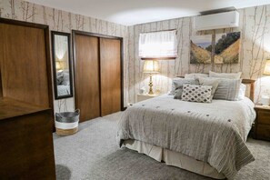 A bedroom with a bed, bedside tables, a lamp, a mirror, and a wardrobe.