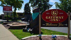 Une enseigne de l’hôtel Gateway Inn, avec une statue d’ours et un panneau indiquant « Bienvenue à votre retour ».