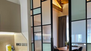 A modern kitchen with a wooden ceiling, a dining area with a table and chairs, and a sliding glass door. - Prisma Suites (Salamanca)