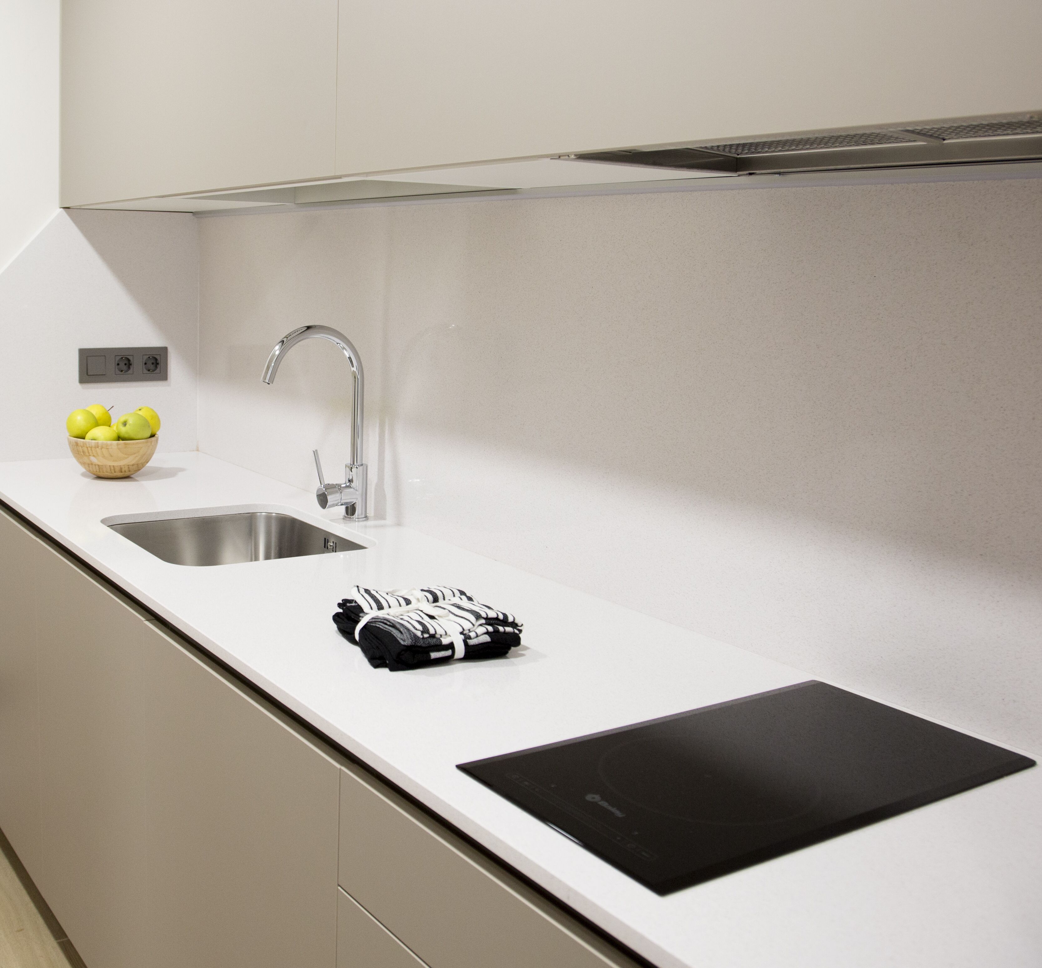 A modern kitchen with a stainless steel sink, a bowl of lemons, and a black cutting board.