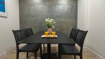 Ett matbord med fyra stolar, en vas med blommor och en tallrik med bakverk och apelsinjuice.