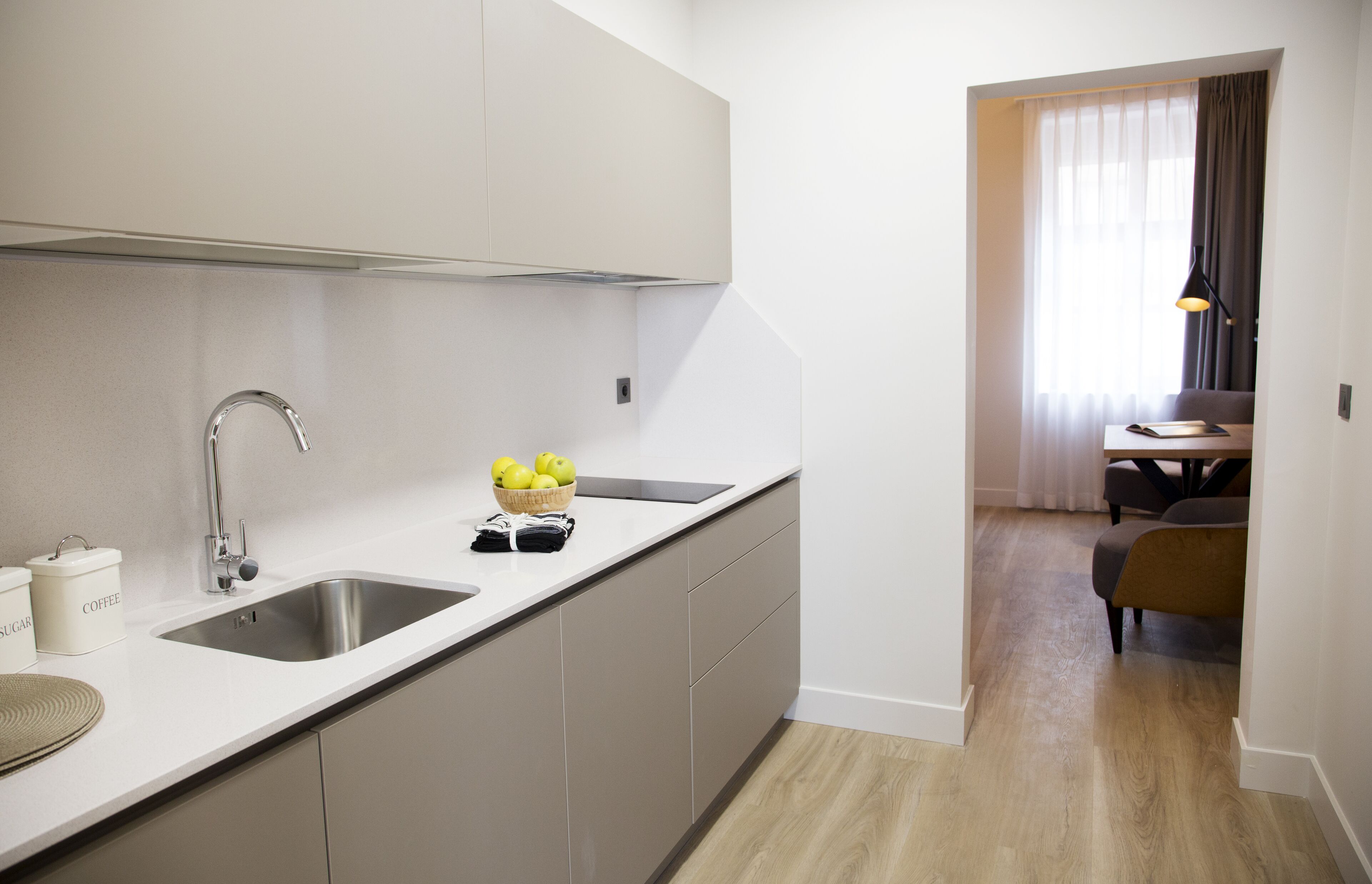 A modern kitchen with a stainless steel sink, a bowl of lemons, and a coffee container.