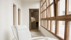 A corridor with a wicker chair and a round table with a magazine. - Prisma Suites (Salamanca)