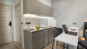 A modern kitchen with a built-in island, a laptop on a small table, and a bowl of fruit on the counter.