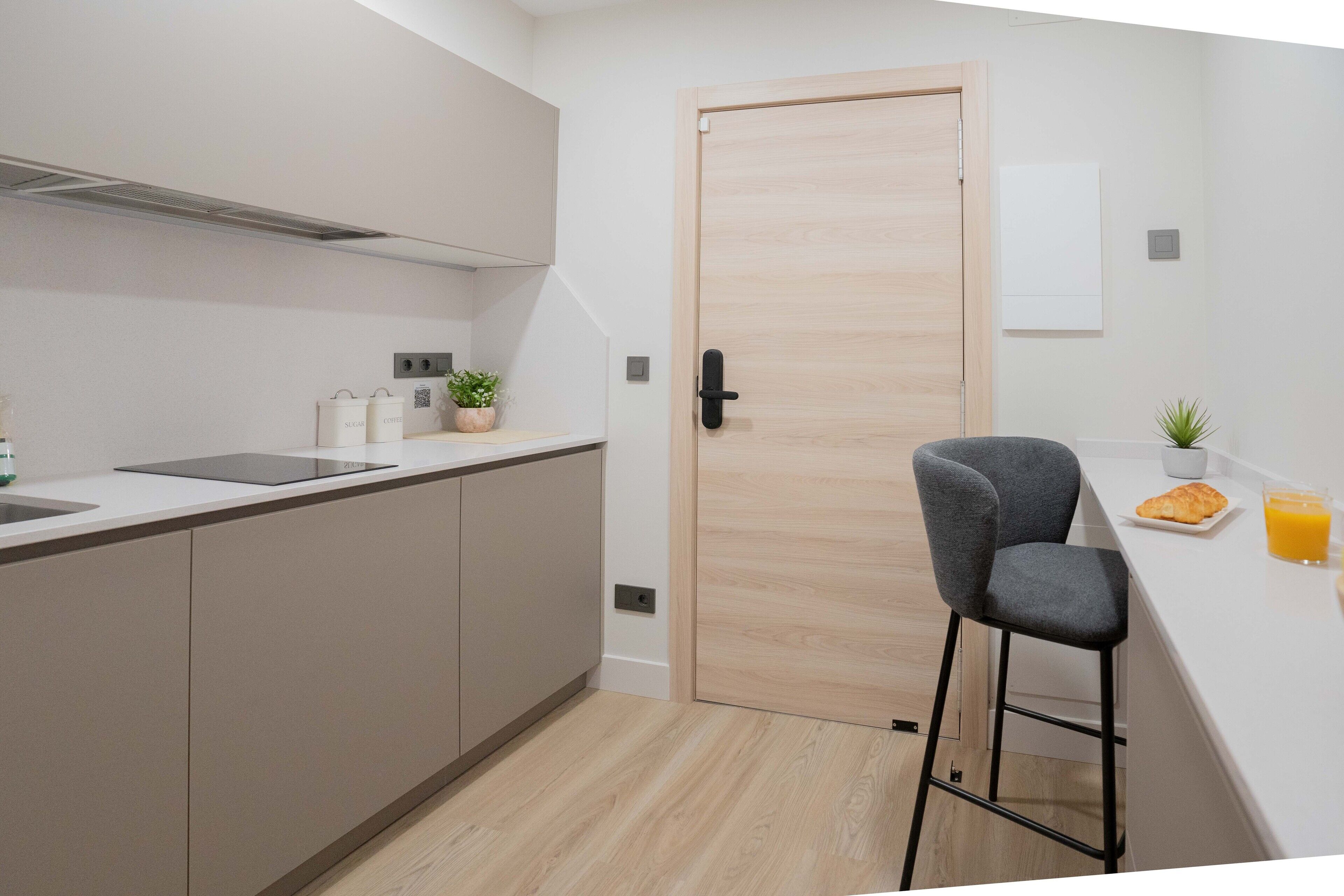 Cozinha moderna com porta de madeira, um banquinho e espaço para café da manhã.