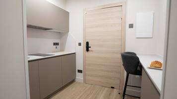 Cocina compacta con puerta de madera, un taburete y una pequeña barra.