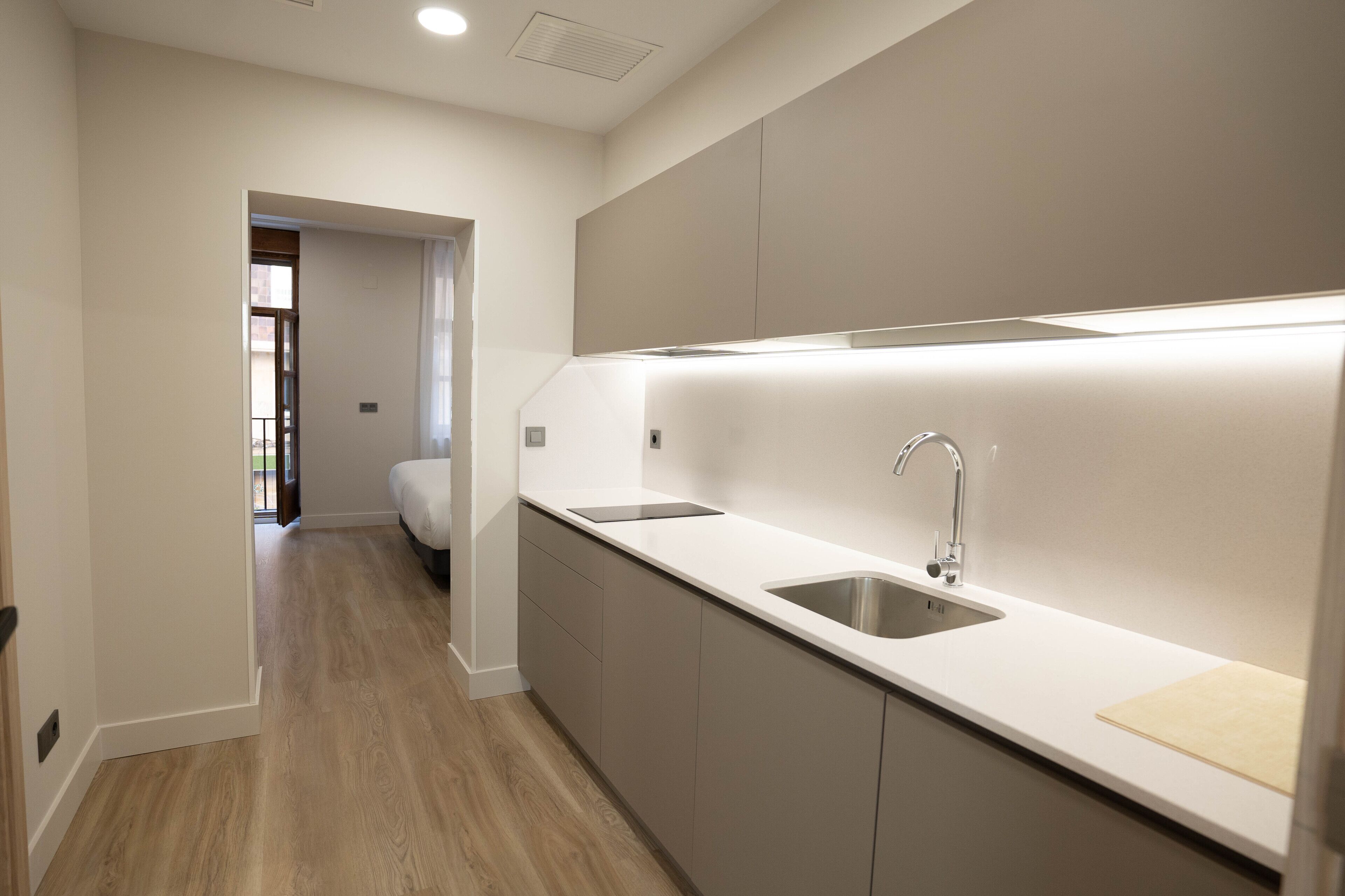 Una cocina moderna con un lavamanos de acero inoxidable, un horno empotrado y una encimera.
