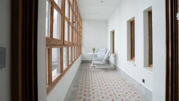 A corridor with patterned flooring, a white chair, and a table with a vase.