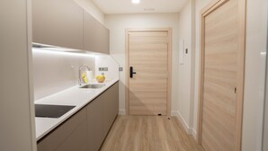A modern kitchen with a sink, countertop, and wooden door. - Prisma Suites (Salamanca)