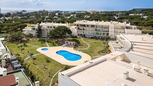 A residential building with a swimming pool, multiple balconies, and a surrounding landscaped area.