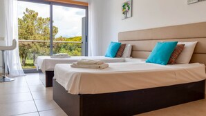 A hotel room with two beds, a large window, and a view of trees.