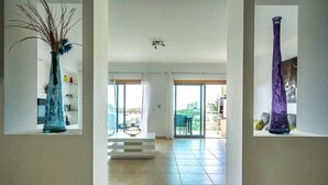 A modern interior with a central staircase, large windows, and two vases on shelves.