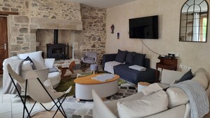 Ein Wohnzimmer mit einer Steinwand, einem Kamin, einer Couch, einem Couchtisch und einem an der Wand befestigten Fernseher.