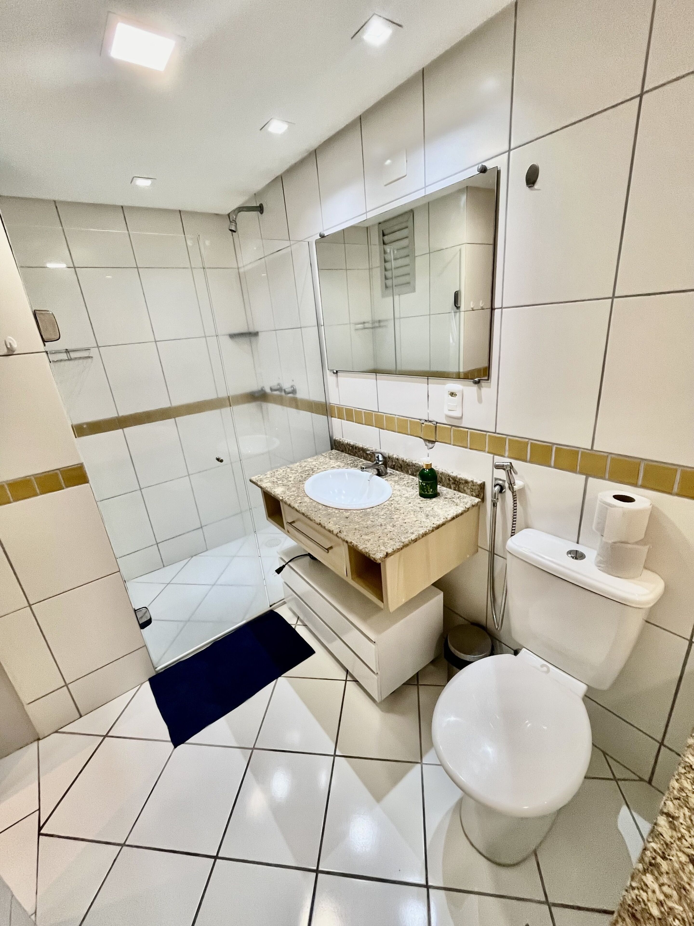 A modern bathroom with a white sink, mirror, and toilet.