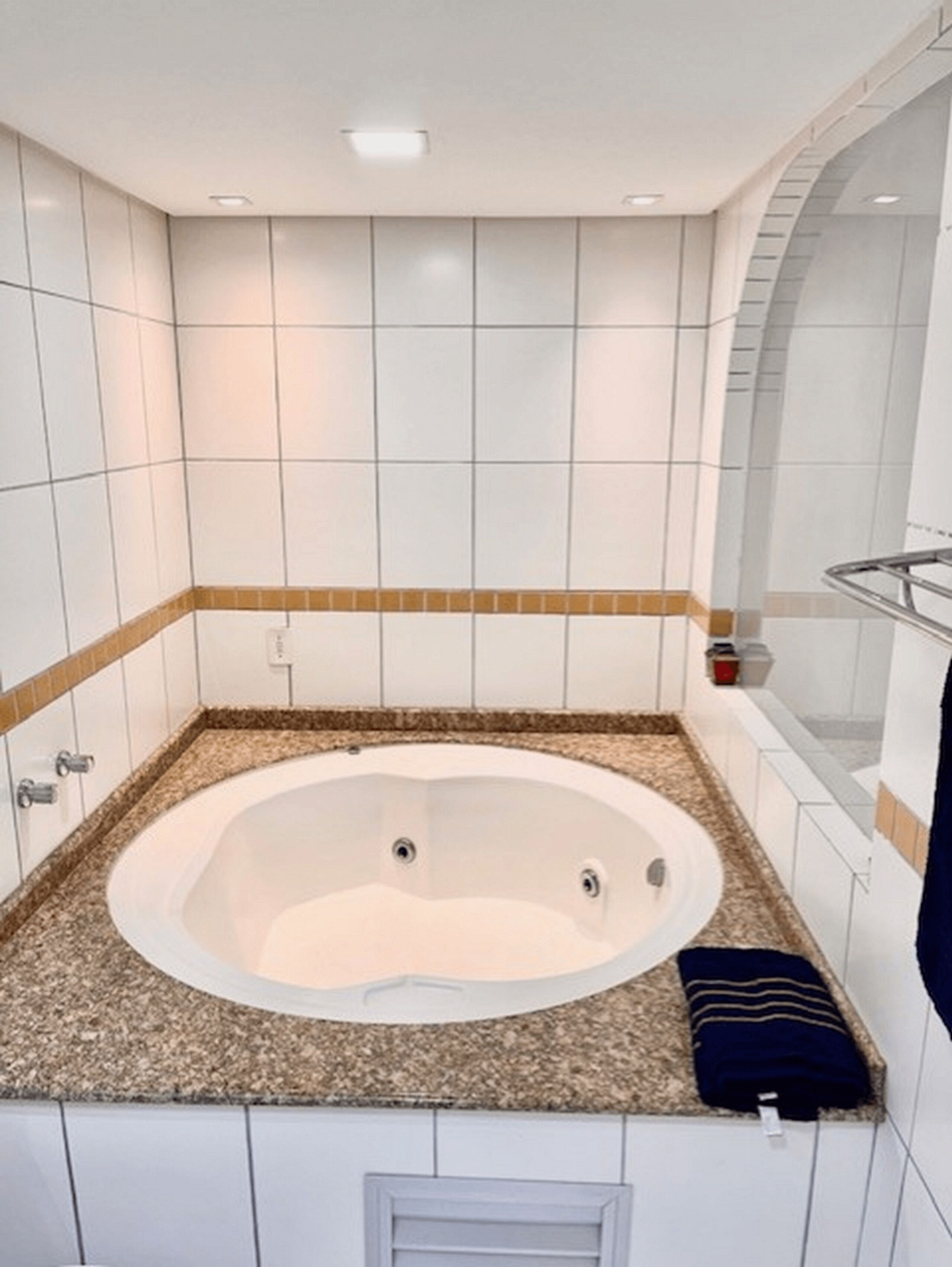 A bathroom with a freestanding bathtub, white tiled walls, and a granite countertop.