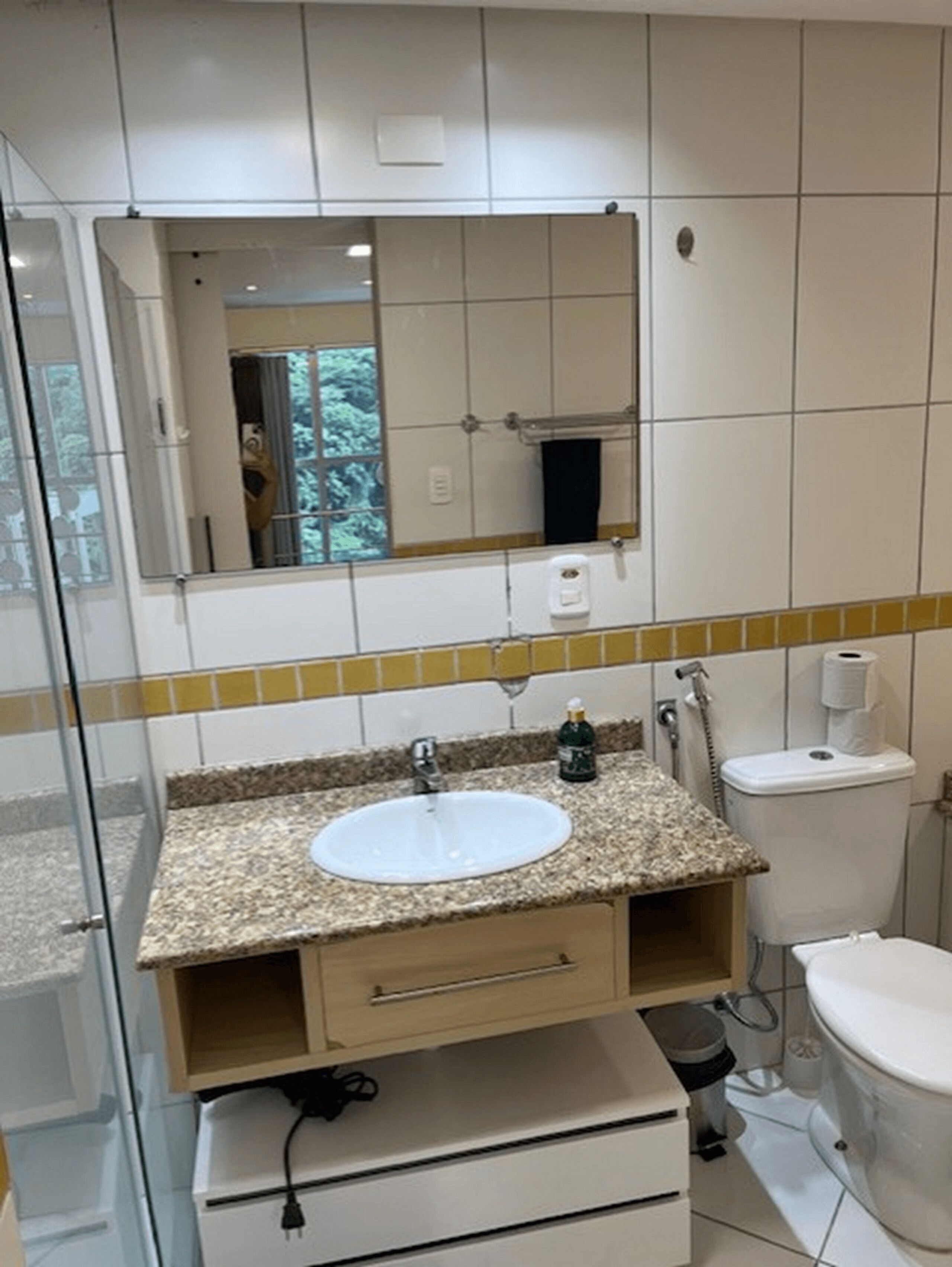 Un baño con lavamanos de encimera de granito, un espejo, un inodoro y una ducha.
