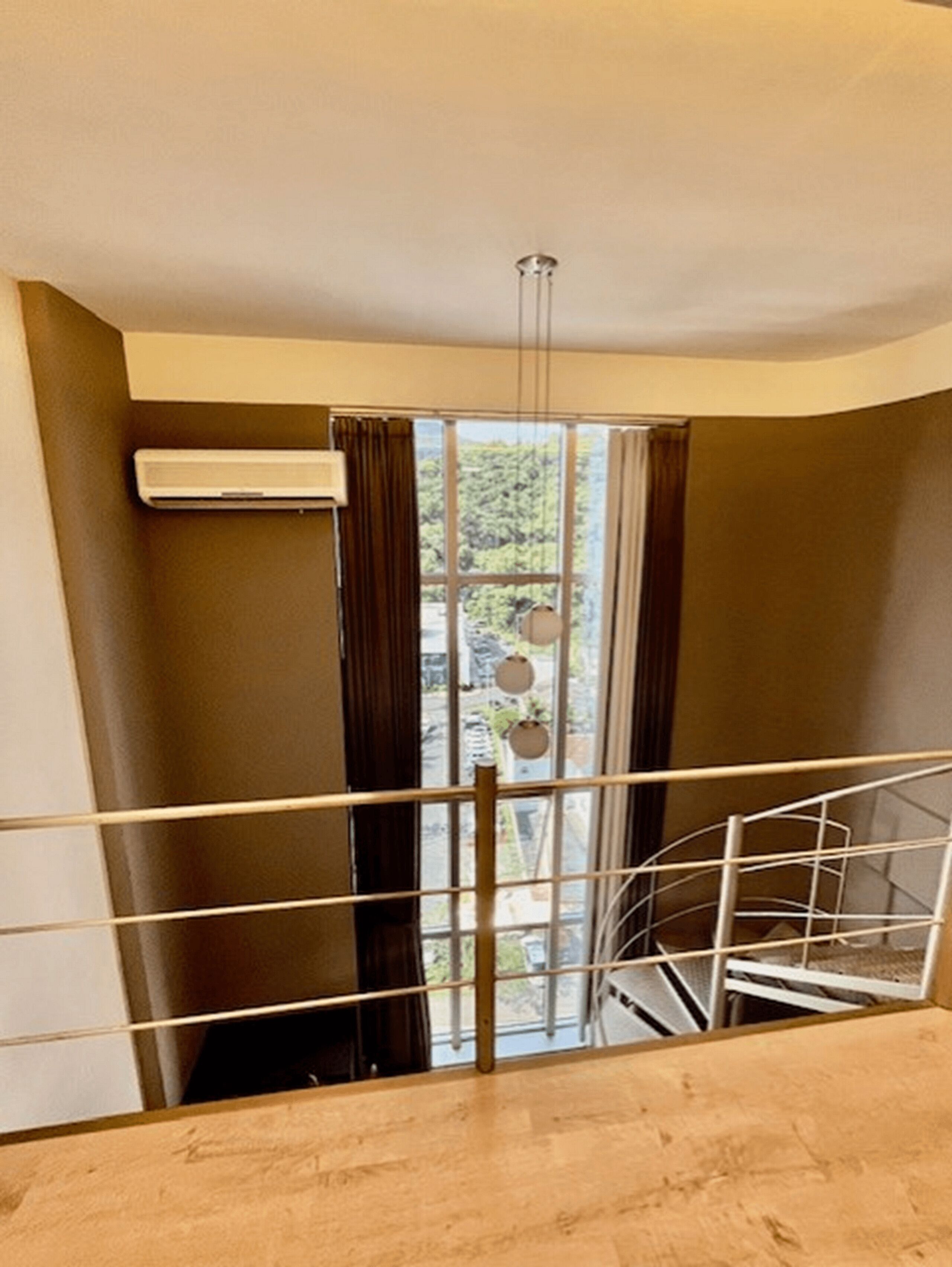 A room with a large window, a metal railing, and a staircase.