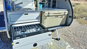 A kitchen area with a stove, sink, and storage cabinets. - Red Rock Base Camps Teardrop Trailer #3. Take your hotel room outside!  (Moab)