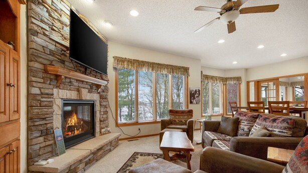 A cozy living room with a stone fireplace, comfortable seating, and large windows. - Soft Landings at the Hangar House! Next to the Clubhouse and Airstrip (Danbury)