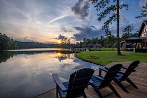 A lakeside deck with Adirondack chairs, a wooden dock, and a gazebo. - Lakefront home. Beach. Kayaks. Dock. Outdoor fireplace & TV. Neighborhood Pool. (Dadeville)