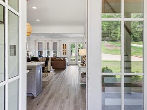 A spacious living area with a large window, a ceiling fan, and a view of the outdoors. - Lakefront home. Beach. Kayaks. Dock. Outdoor fireplace & TV. Neighborhood Pool. (Dadeville)